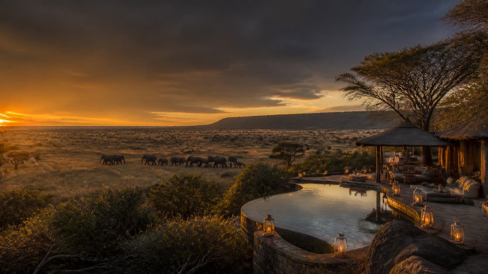 Private safari camp overlooking elephants crossing the savannah at sunset